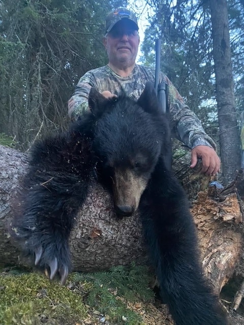 Hunter with harvested black bear in boreal forest