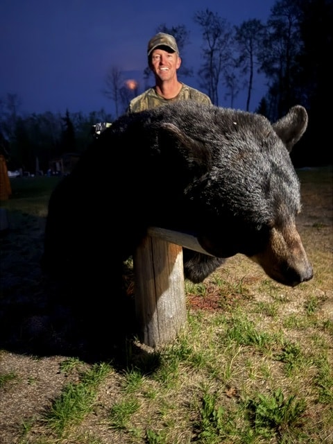 Hunter with large black bear at dusk Saskatchewan