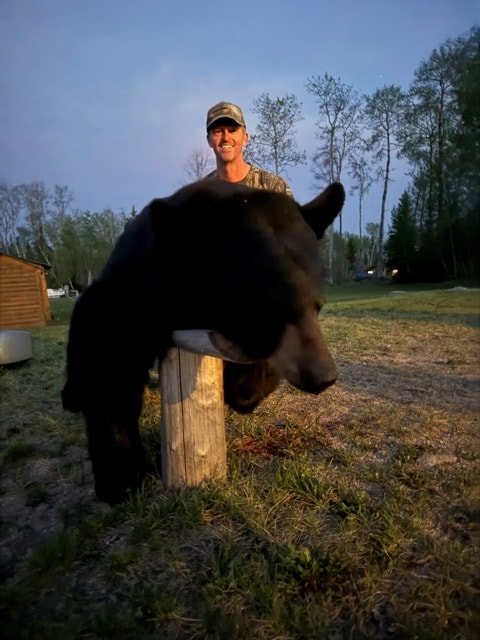 Hunter with large black bear at dusk Saskatchewan wilderness