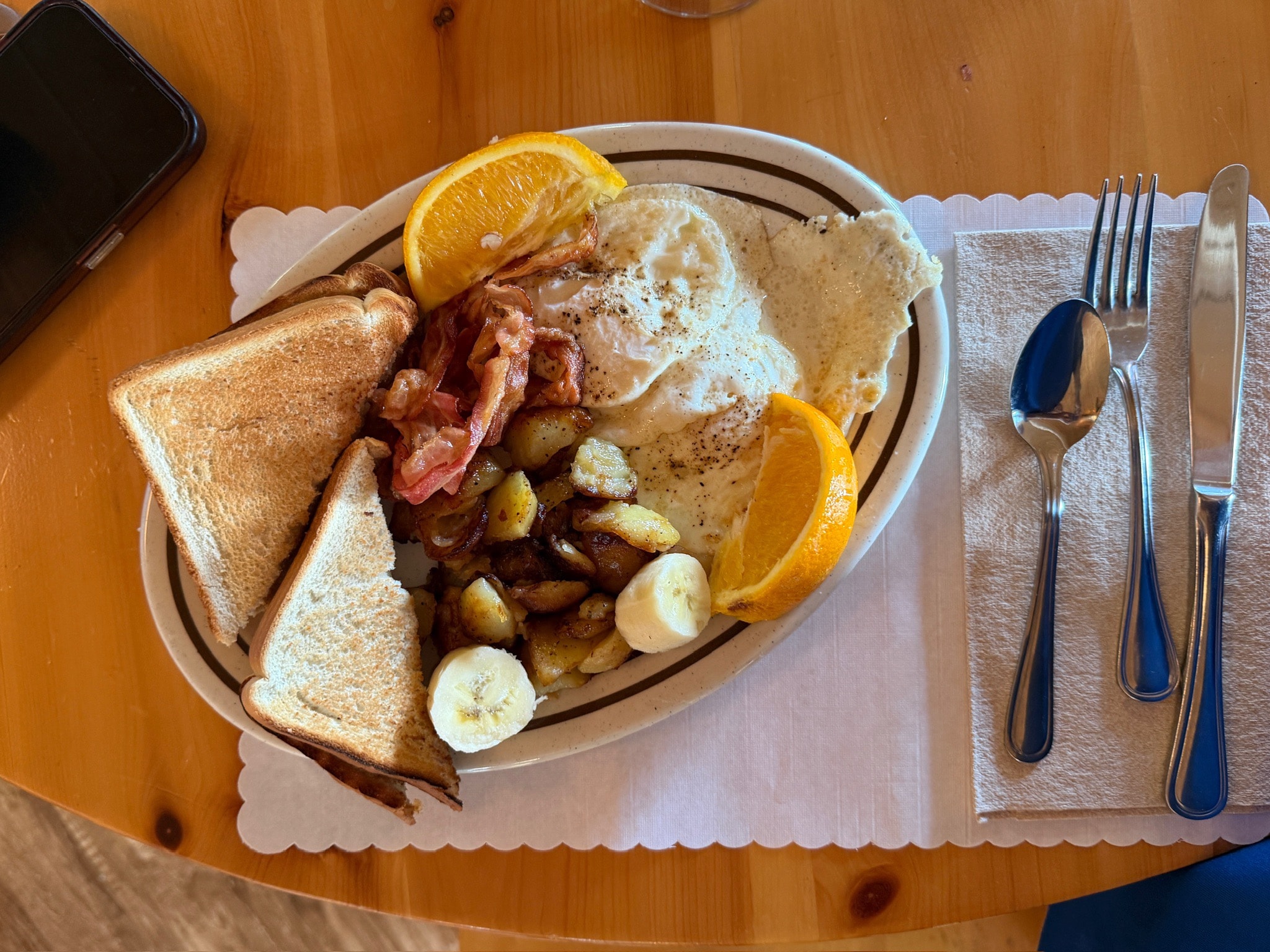 Full lodge breakfast spread — eggs, bacon, home fries, toast, and fresh fruit