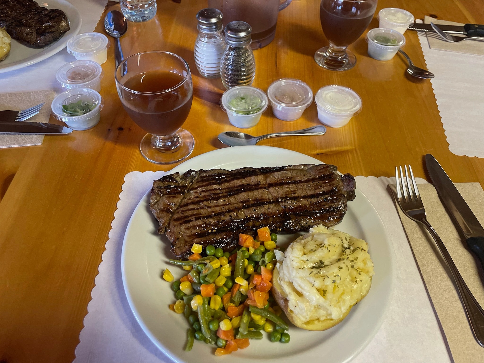 Grilled steak with vegetables and baked potato at the lodge dinner table