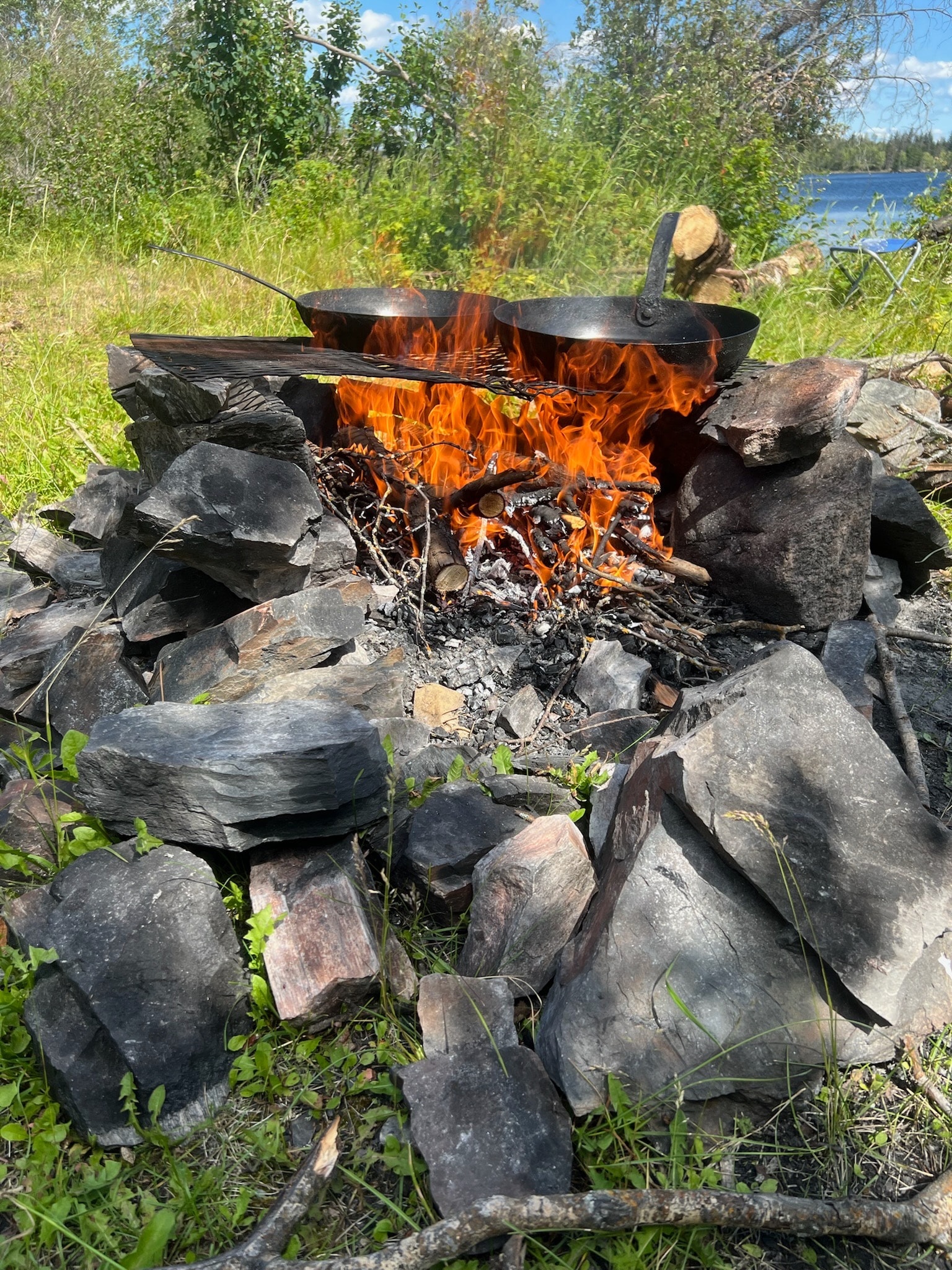 Campfire cooking pot over flames lakeside
