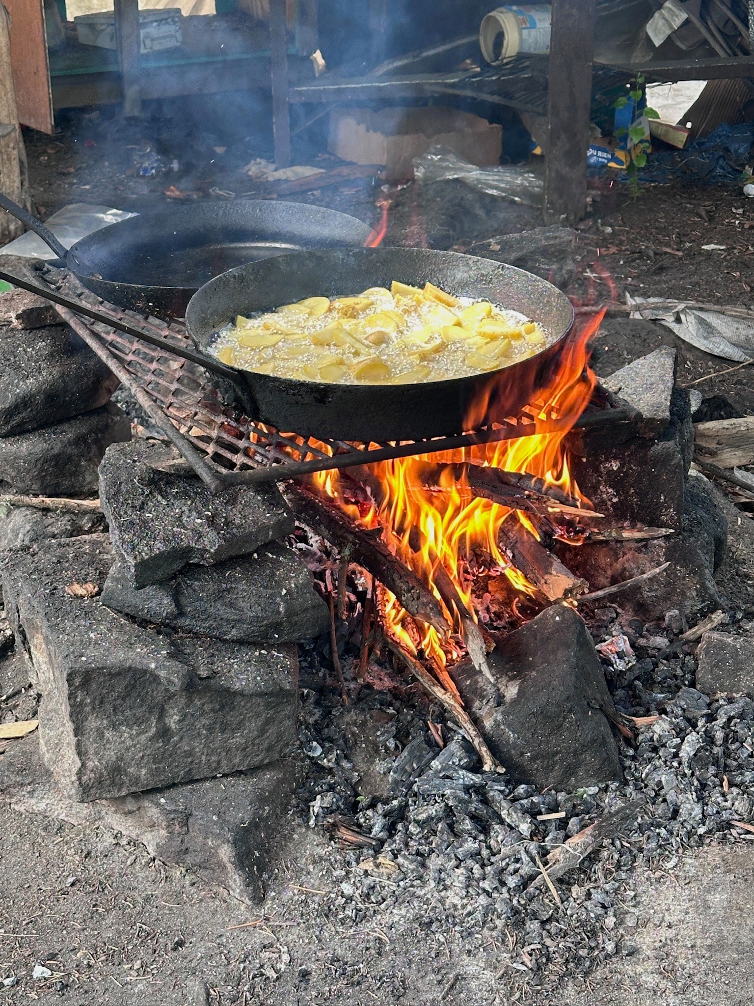 Potatoes frying in cast iron pan over campfire
