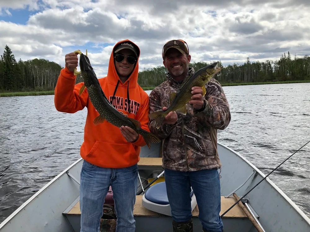 Two men holding caught fish on boat, Black Bear Island Lodge