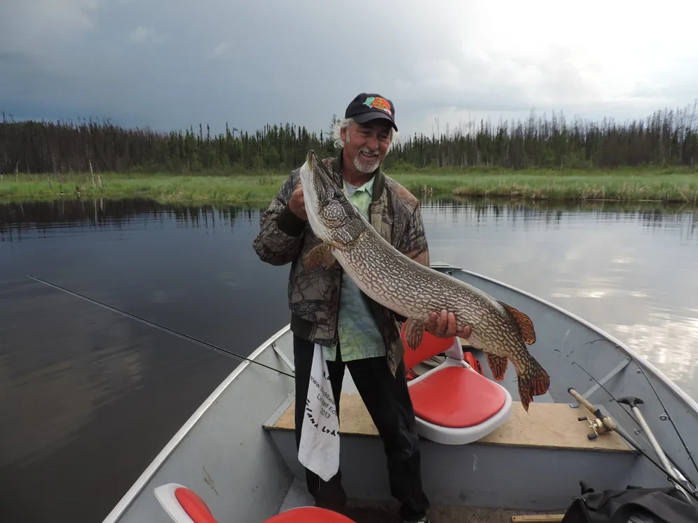 Man holding a large Northern Pike on a wilderness river