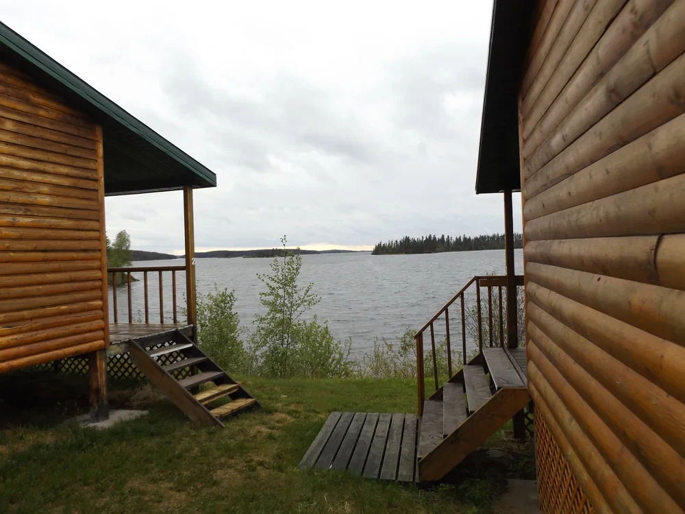 Log cabins with covered porches and lake view between them