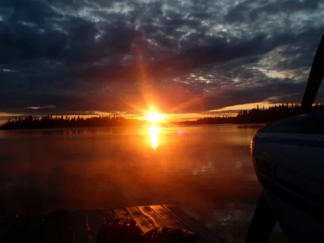Fiery sunrise over the lake with floatplane docked at the dock