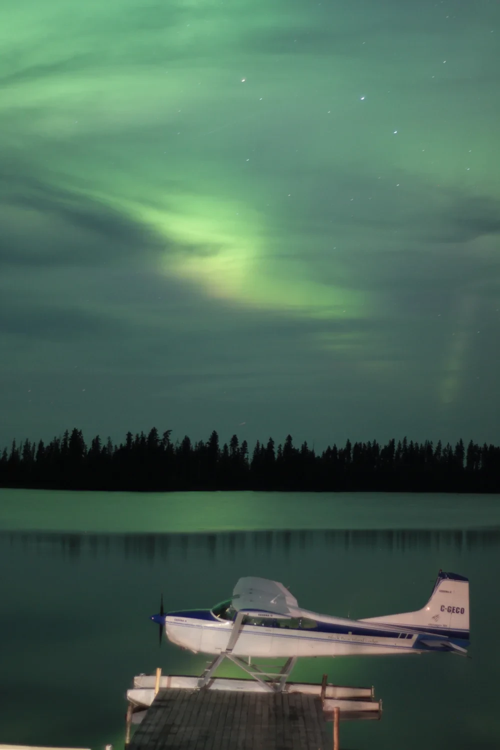 Floatplane docked on a calm lake under the northern lights
