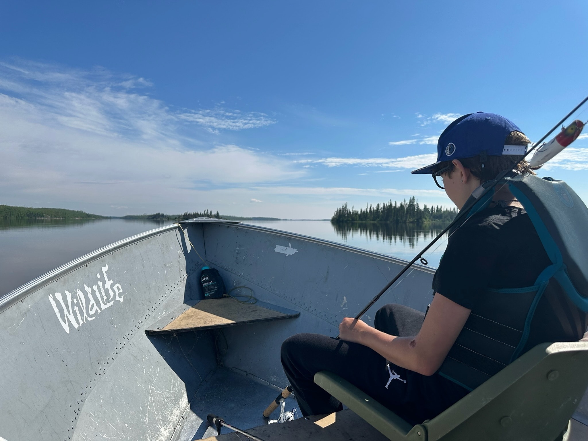 Young angler fishing from a boat on a calm wilderness lake