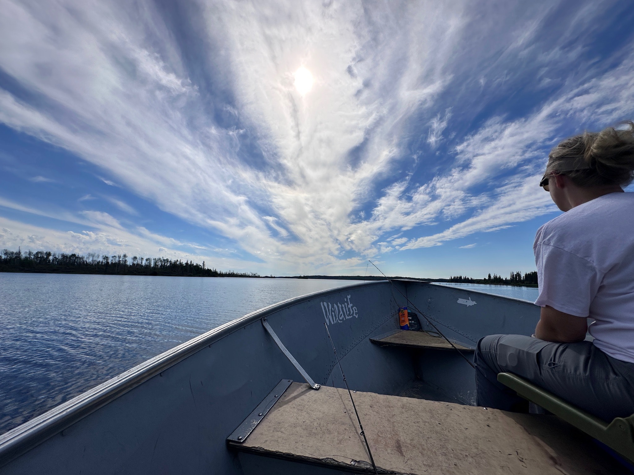 View from the bow of an aluminum fishing boat under a dramatic cloud-streaked sky