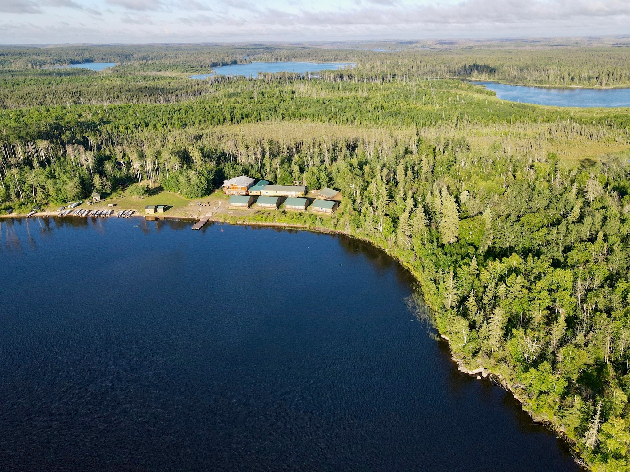 Wide aerial view of Black Bear Island Lodge nestled in boreal forest on the lakeshore