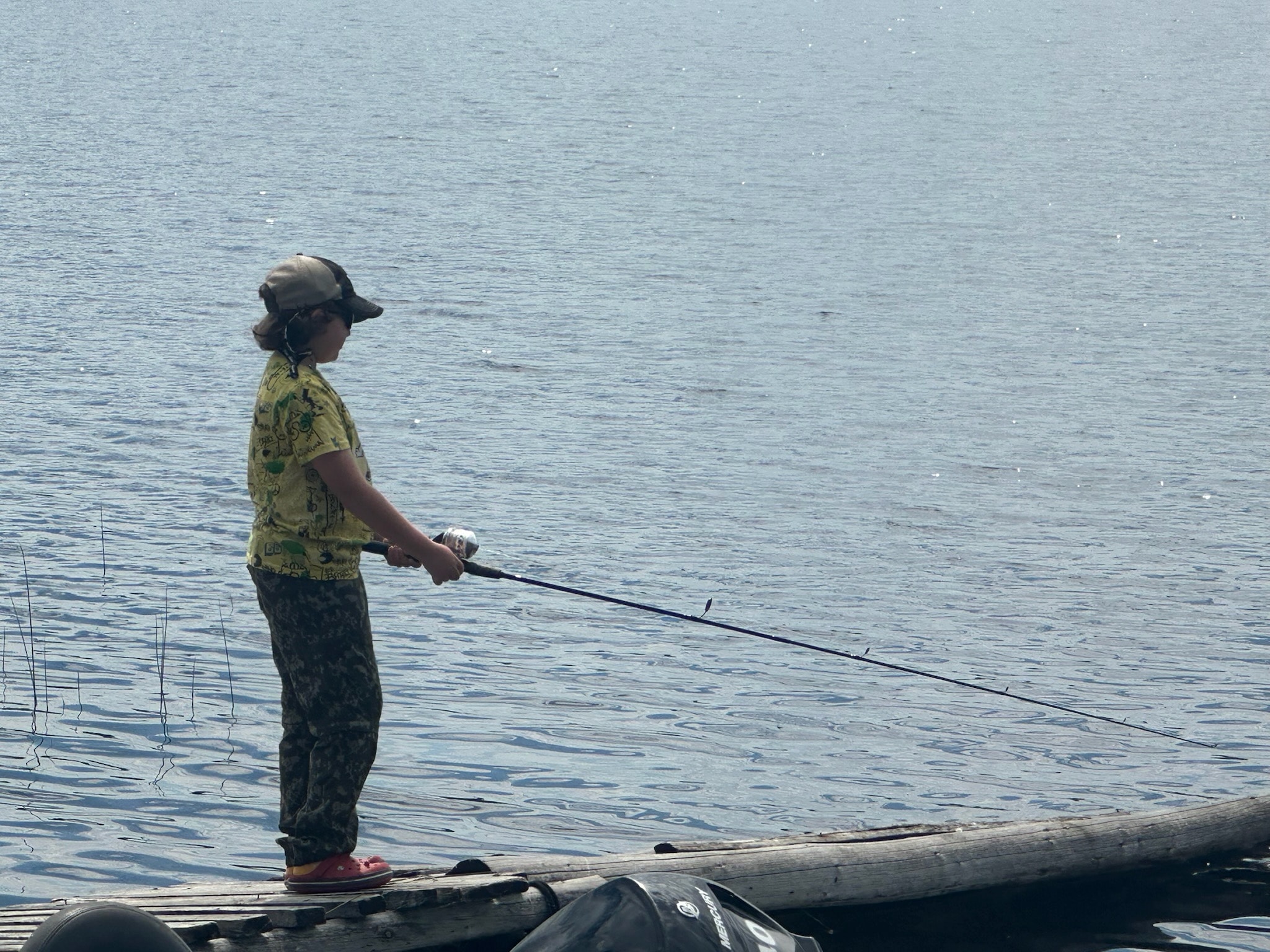 Young child in camo gear fishing from the dock with a spinning rod